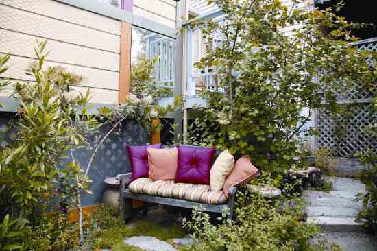 A terraced outdoor seating area features brightly colored pillows. The wall’s painted trim, sculptural objects and a mirror liven what was once dead space.